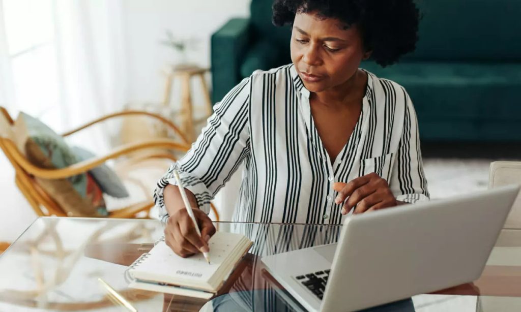 Femme prenant des notes devant un ordinateur portable — réflexion sur l’investissement en unités de compte en assurance vie