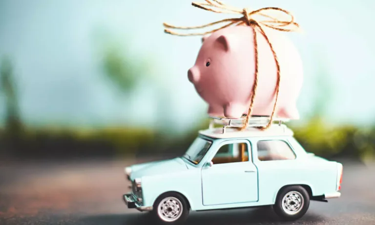 Petite voiture bleue transportant une tirelire cochon rose sur le toit — idée d’épargne mobile pour ouvrir un PER (Plan d’Épargne Retraite)