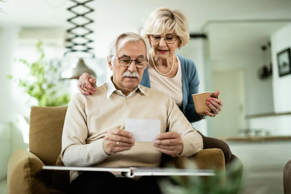 Couple de seniors assis à domicile consultant un document lié à leur retraite ou à leur épargne