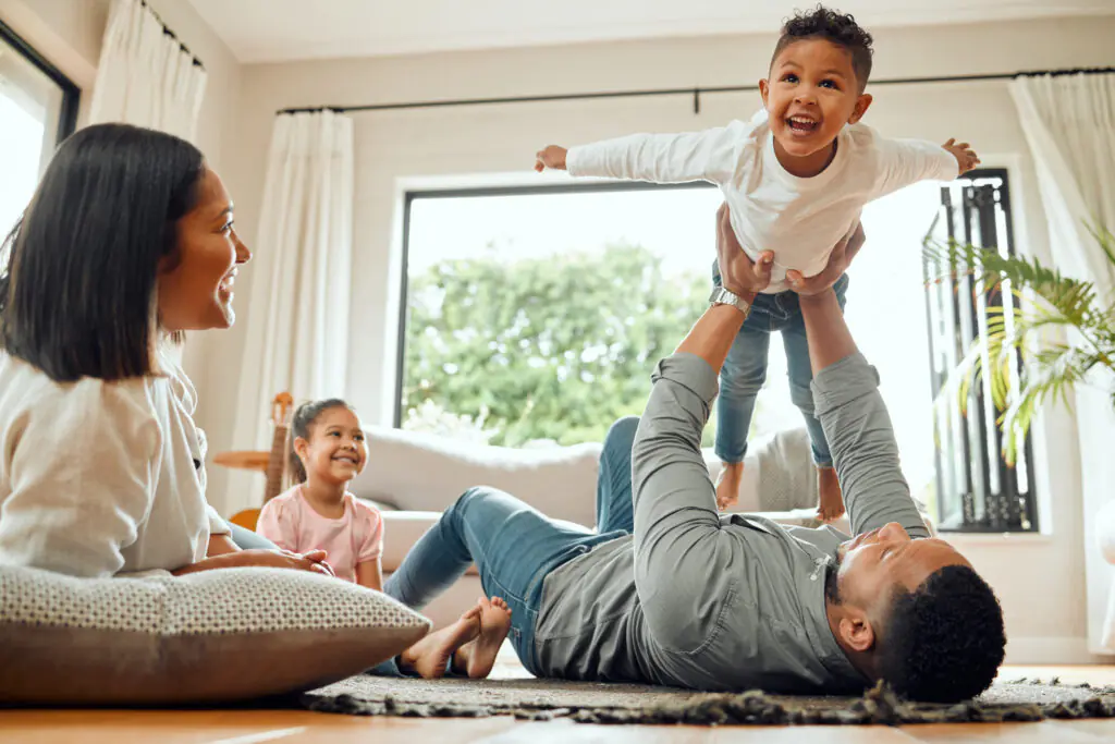 Famille souriante jouant ensemble dans le salon, illustrant la sécurité financière et familiale