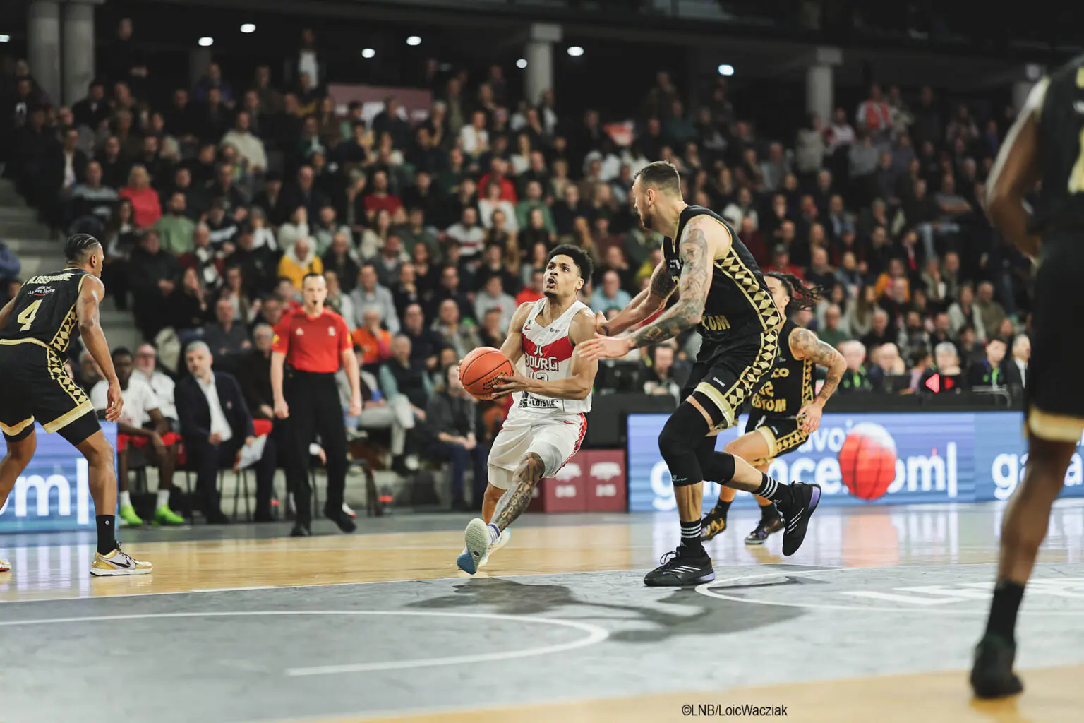 ©LNB/LoicWacziak Joueur lançant une attaque dynamique dans un match, avec branding Garance sur le terrain visible