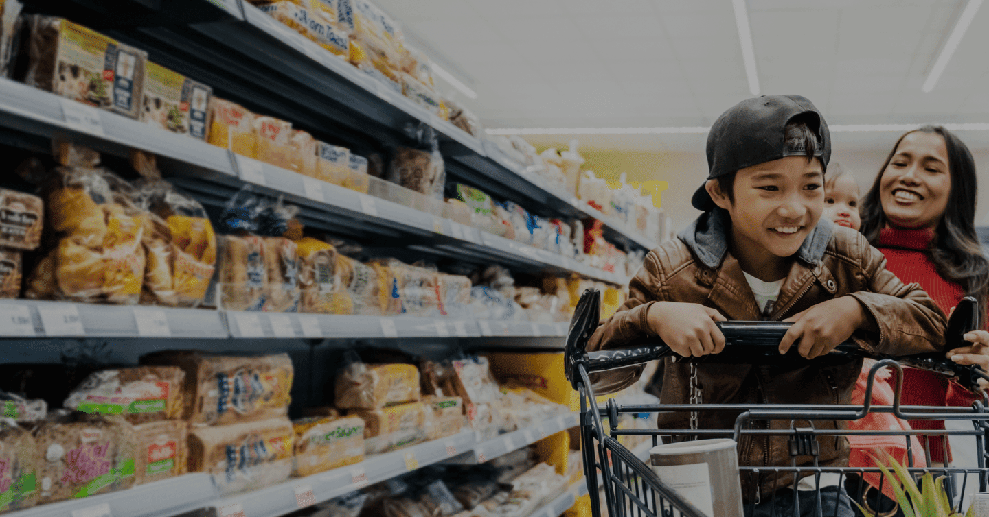 Mère et fils souriants faisant les courses au supermarché, symbole de sécurité financière familiale
