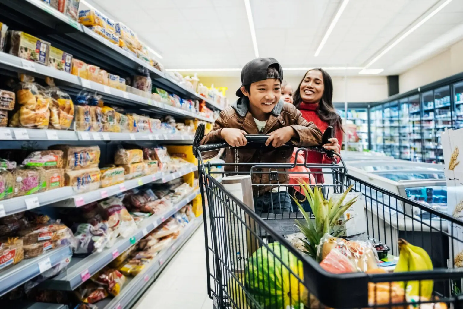 Mère et fils souriants faisant les courses au supermarché, symbole de sécurité financière familiale