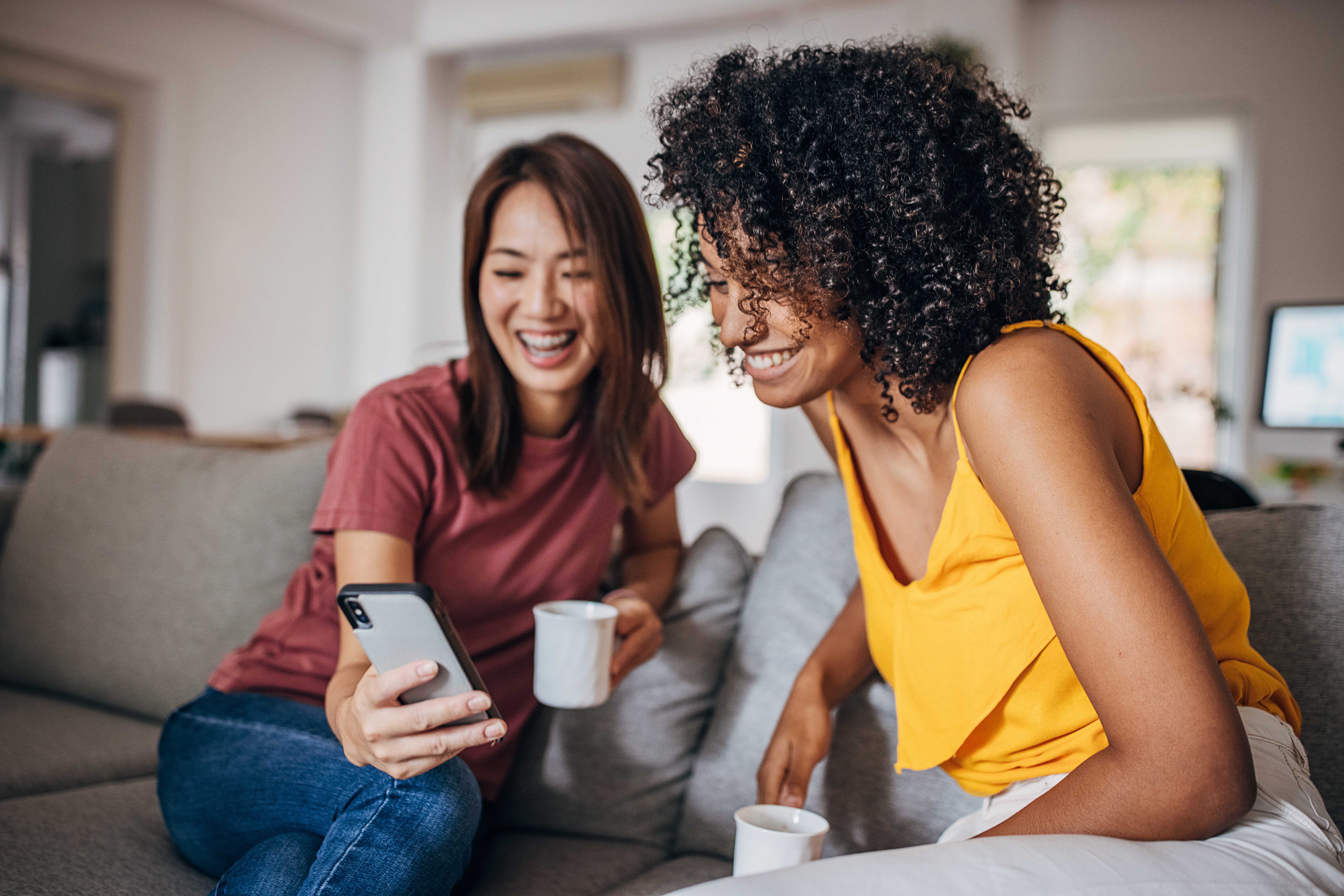 Deux femmes souriantes regardant un smartphone, symbole de convivialité et de partage