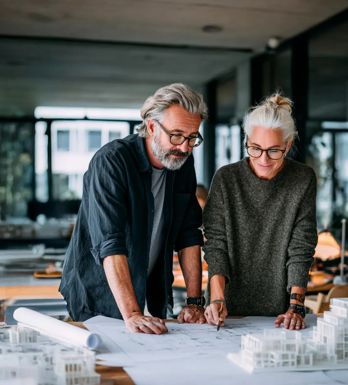 Homme et femme en réflexion devant un plan d'architecte illustrant une image employeur positive