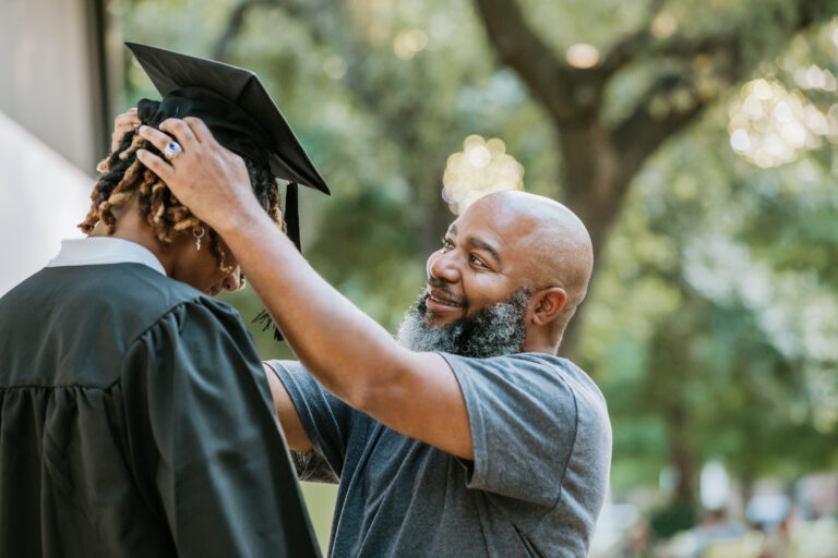 Un père ajuste la toque de remise de diplôme de son enfant
