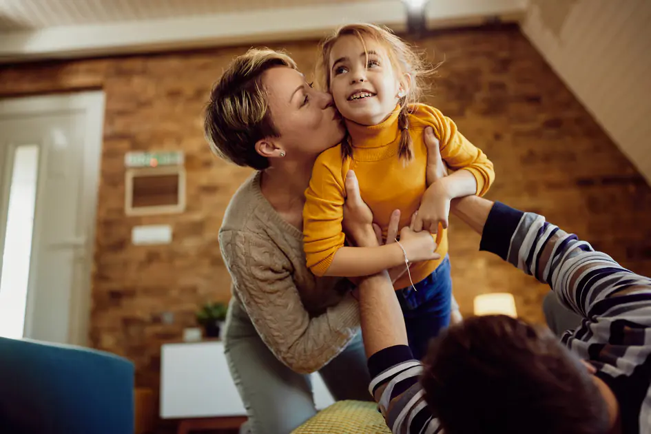 Parents jouant avec leur petite fille à la maison, moment de complicité familiale illustrant la préparation de l’avenir d’un enfant.