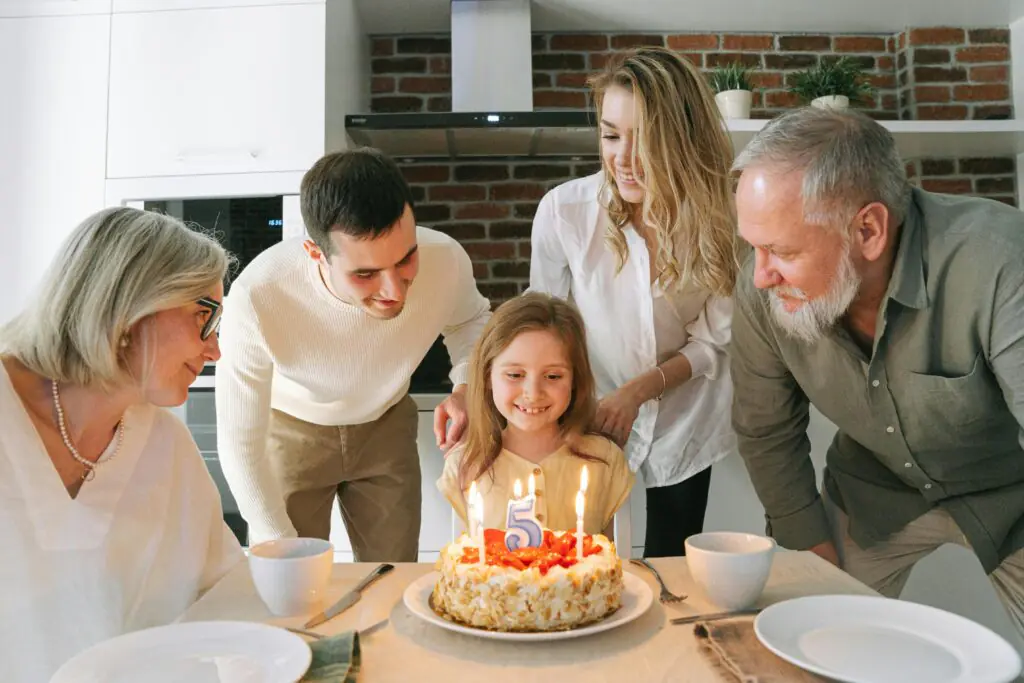 Famille réunie autour d’un gâteau d’anniversaire pour célébrer une enfant, symbole d’épargne et de projets pour l’avenir.