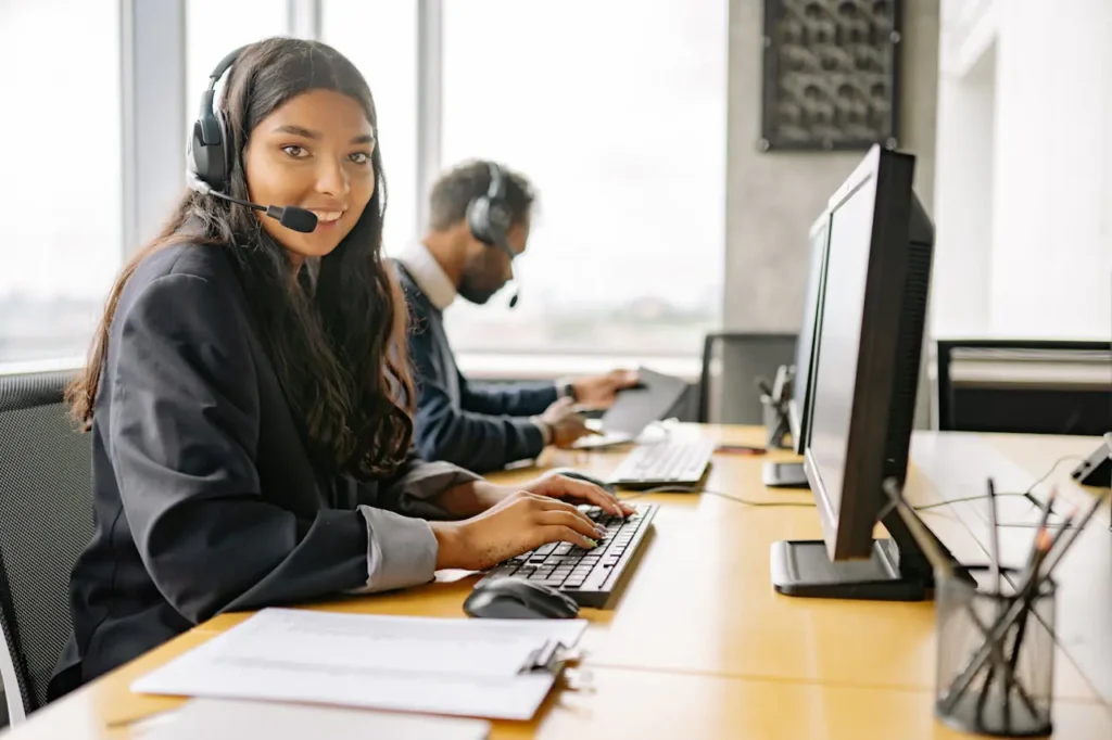 Conseillère en relation client avec casque micro, en échange avec des clients depuis un bureau.
