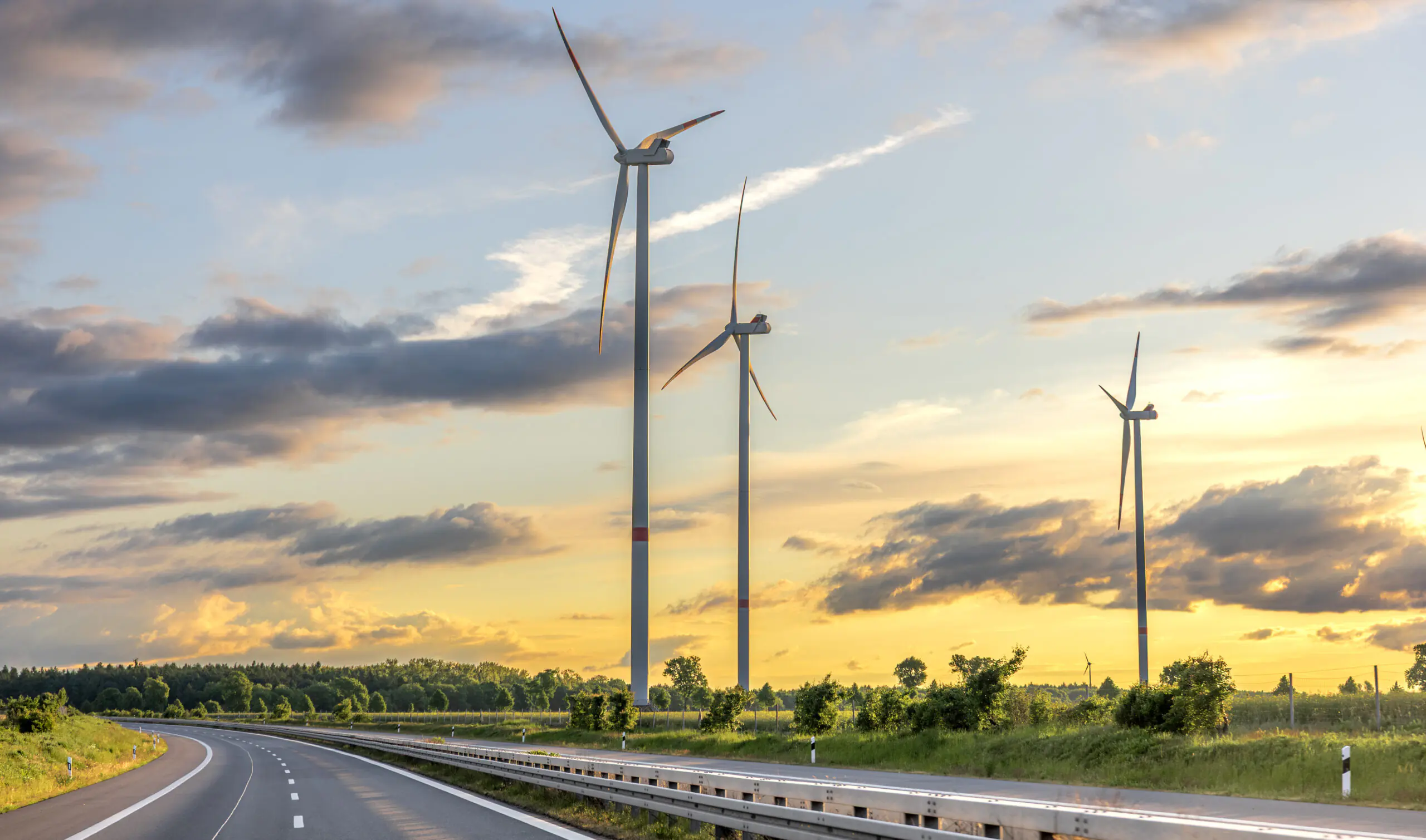 Wind turbines at sunset. Road in field. Rural landscape.