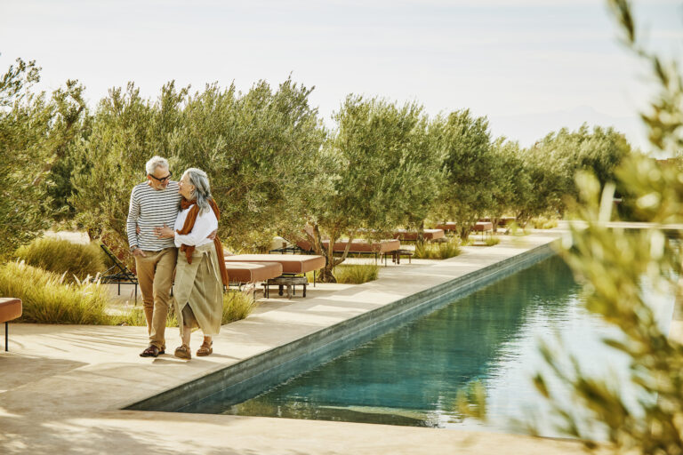 Couple de seniors marchant au bord d’une piscine pendant un séjour