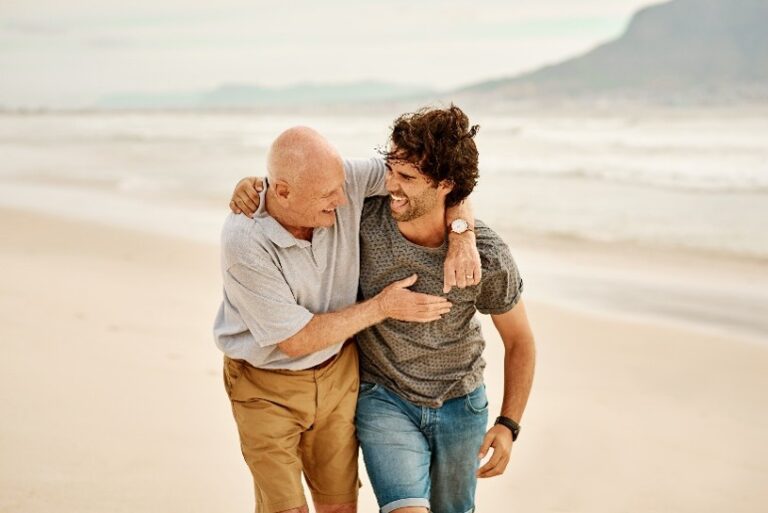 Un homme âgé et un homme plus jeune marchent ensemble sur une plage